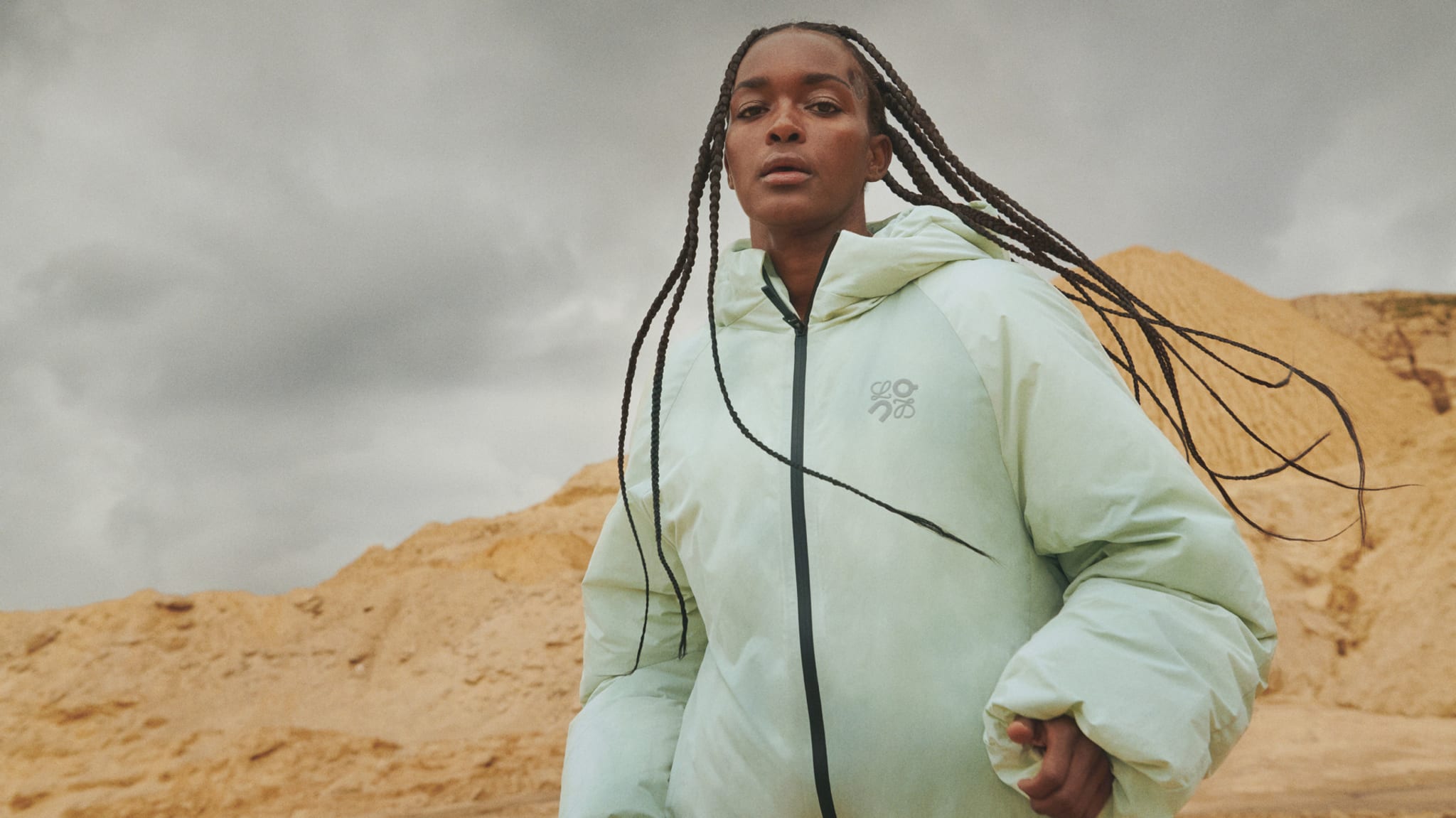 Person in a light jacket with hood outdoors. Fashion-forward with a minimalist vibe