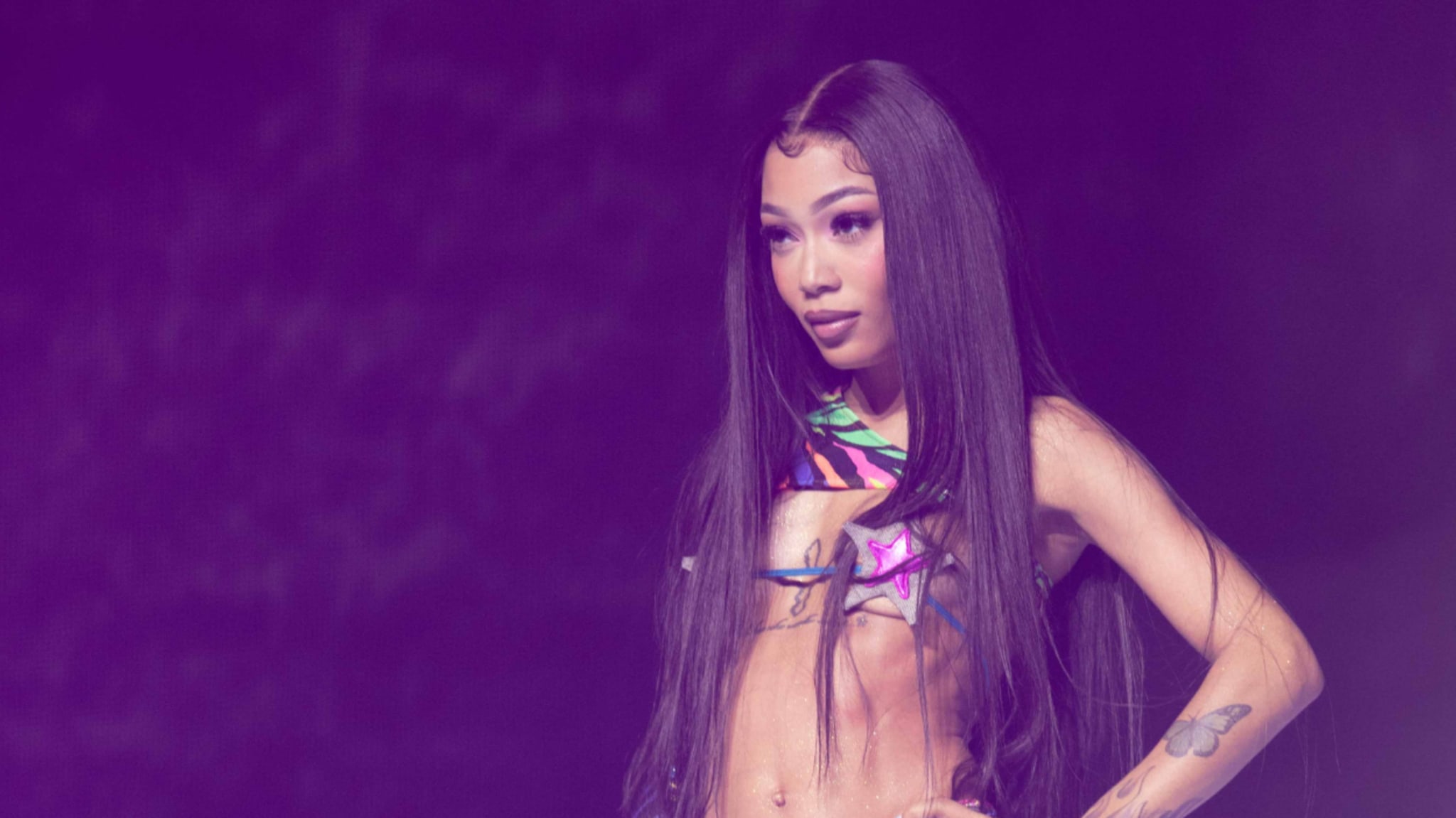 Coi Leray on stage wearing a unique strappy top; performing at an event