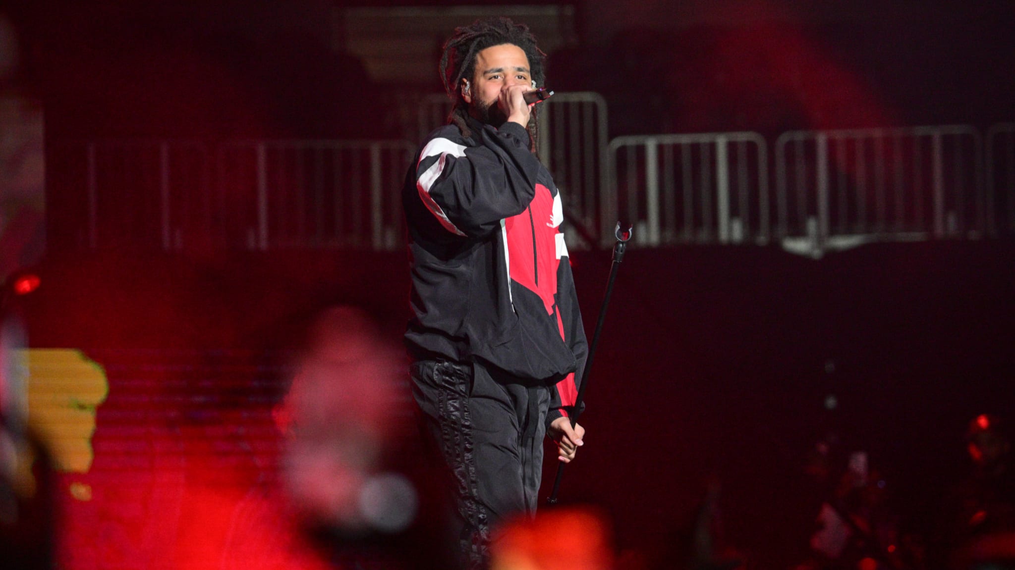 Music artist performing on stage wearing a black and red jacket