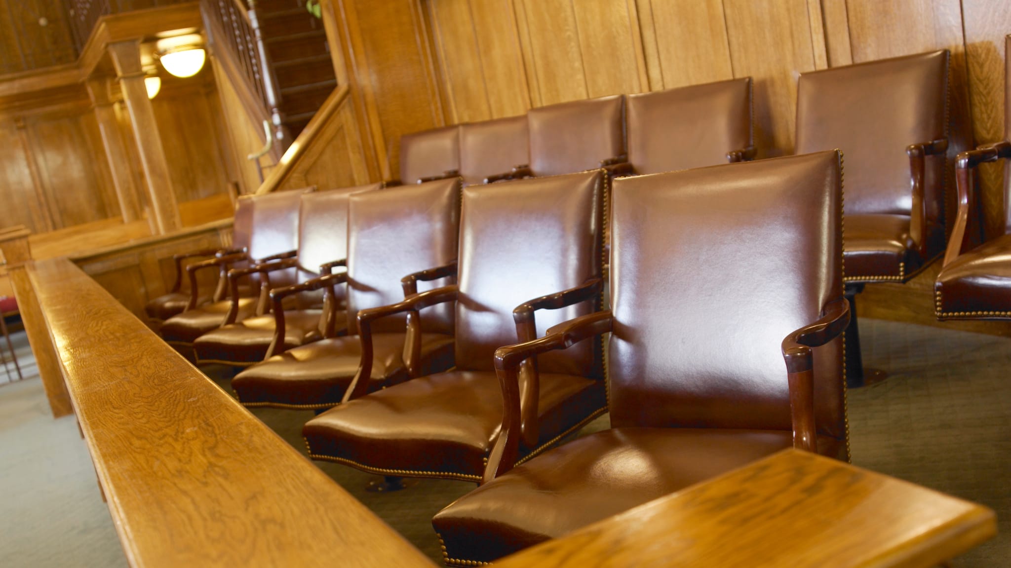 Row of empty leather chairs inside a traditional wood-paneled room, possibly a courtroom or formal setting