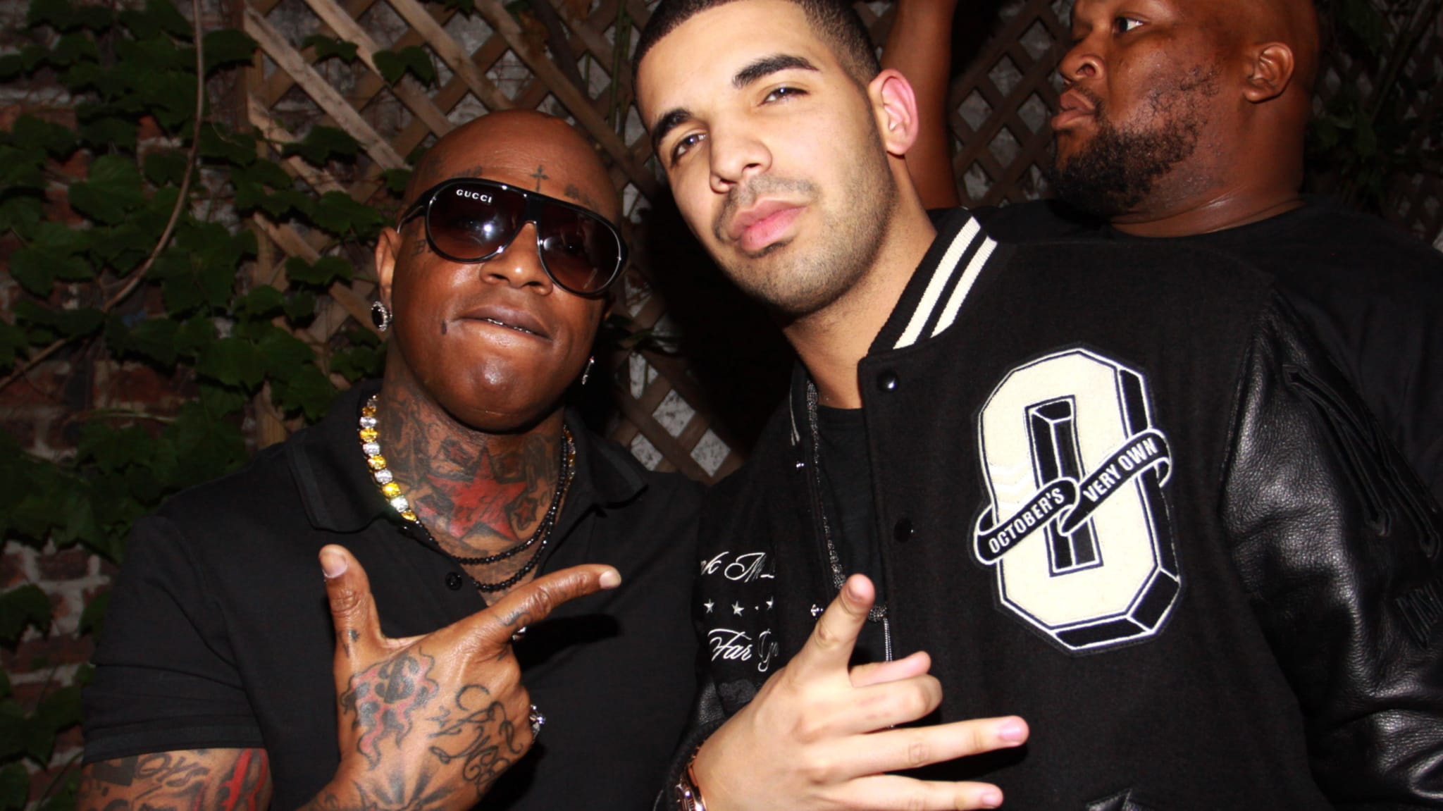 Two male musicians posing for a photo; one in a letterman jacket, the other in a black T-shirt with accessories
