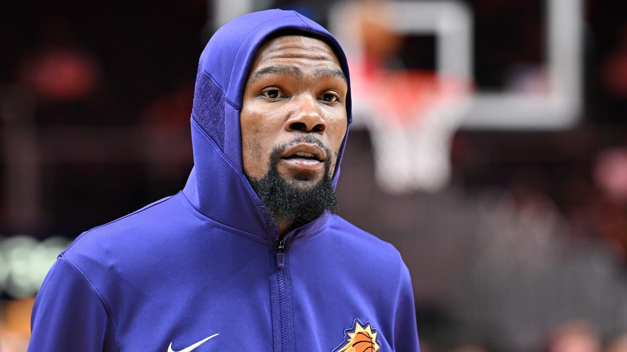 Basketball player wearing team hoodie, looks on pensively