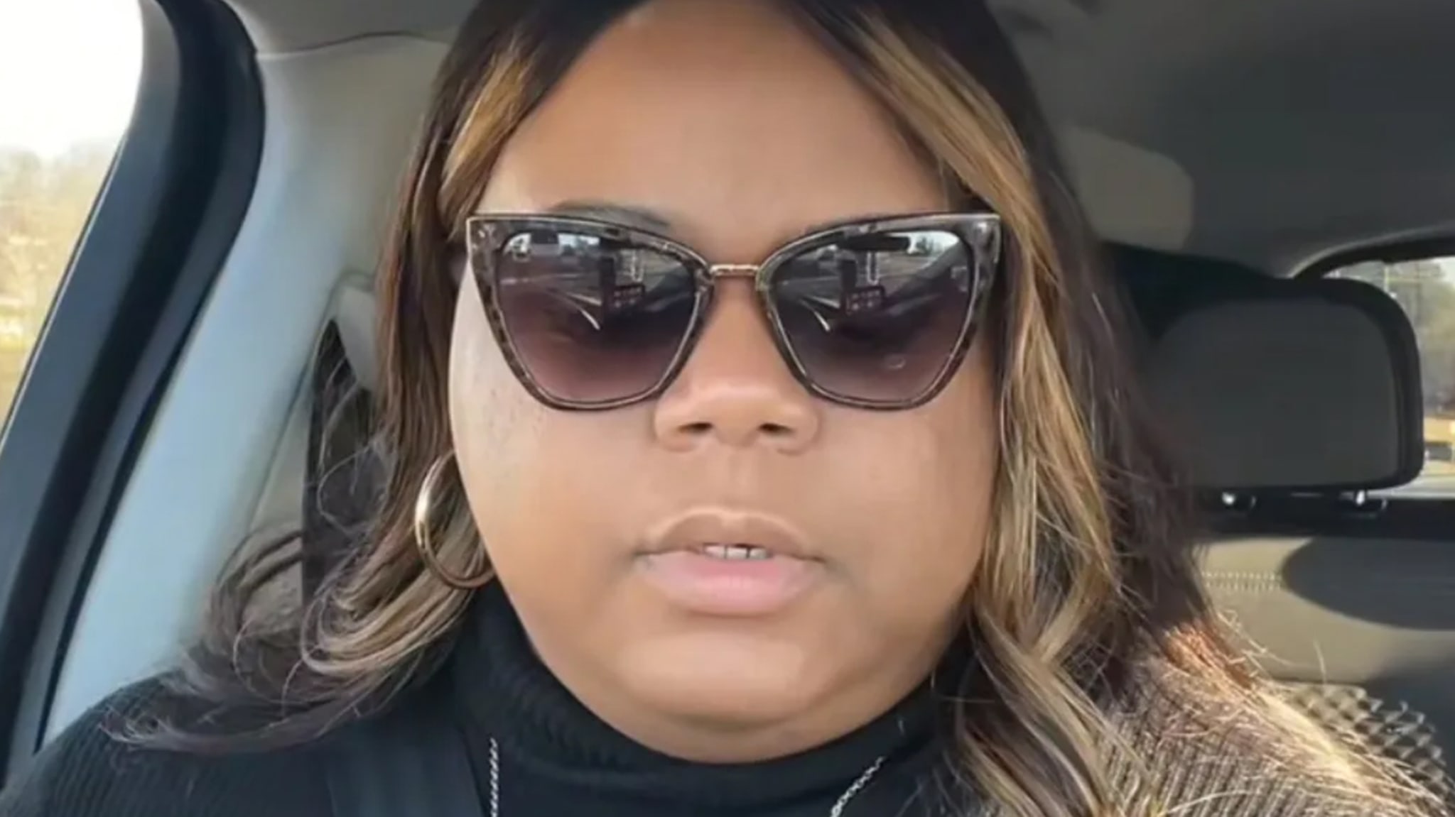 Woman in sunglasses and a turtleneck sitting in a car