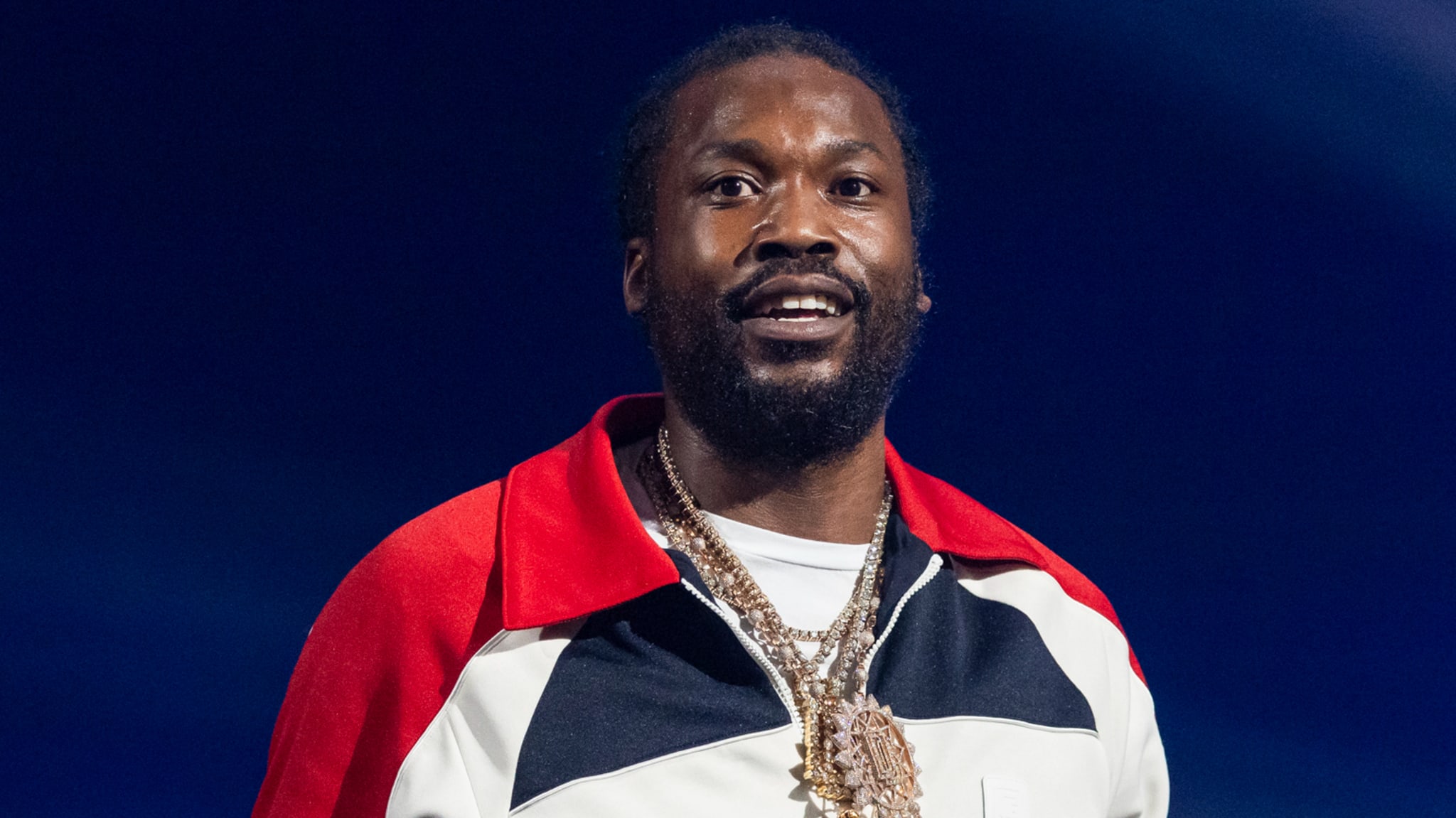 Hip-hop artist on stage in a microphone with a relaxed posture wearing a casual jacket and chain necklace