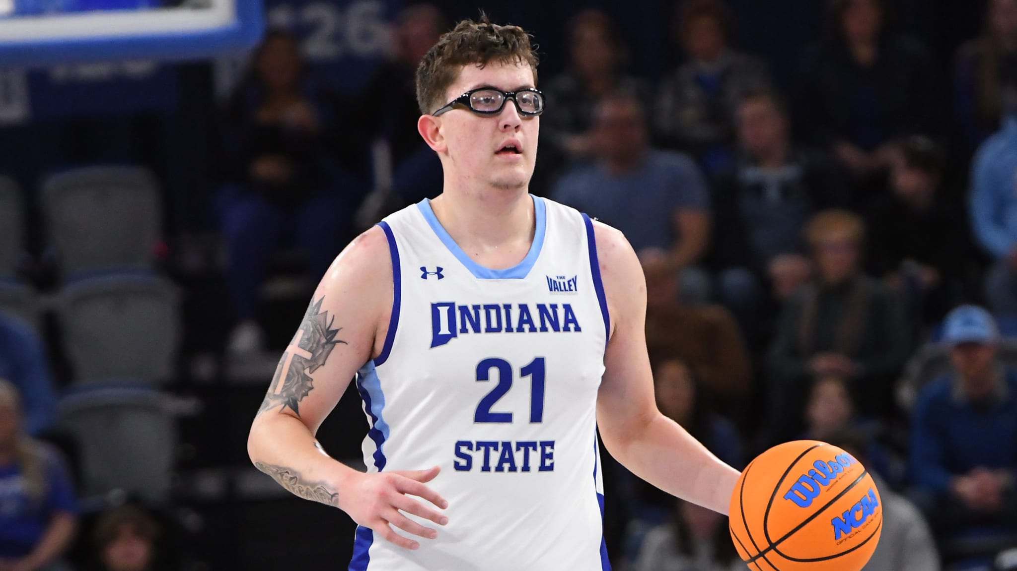 Basketball player in Indiana State uniform dribbling the ball on the court