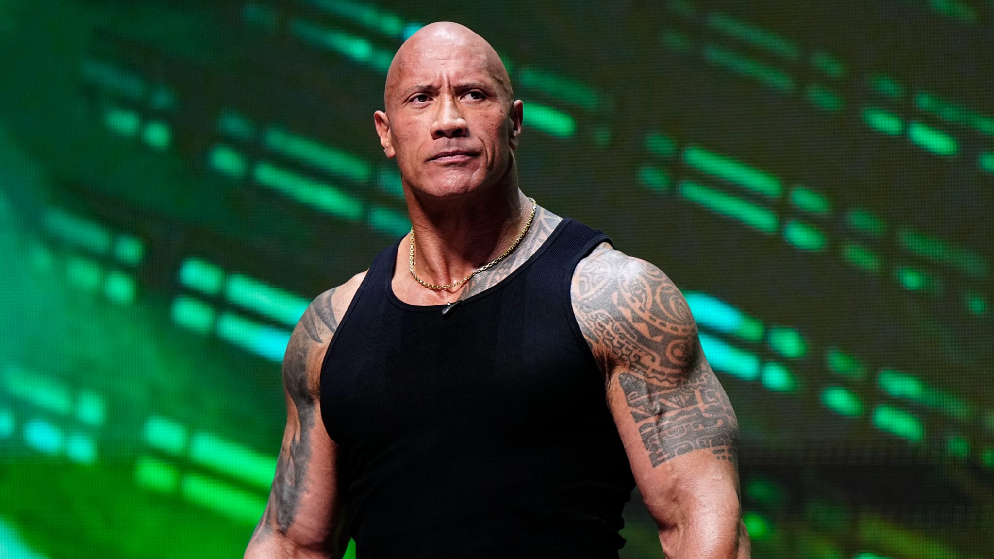 Man on stage wearing sleeveless top with digital backdrop