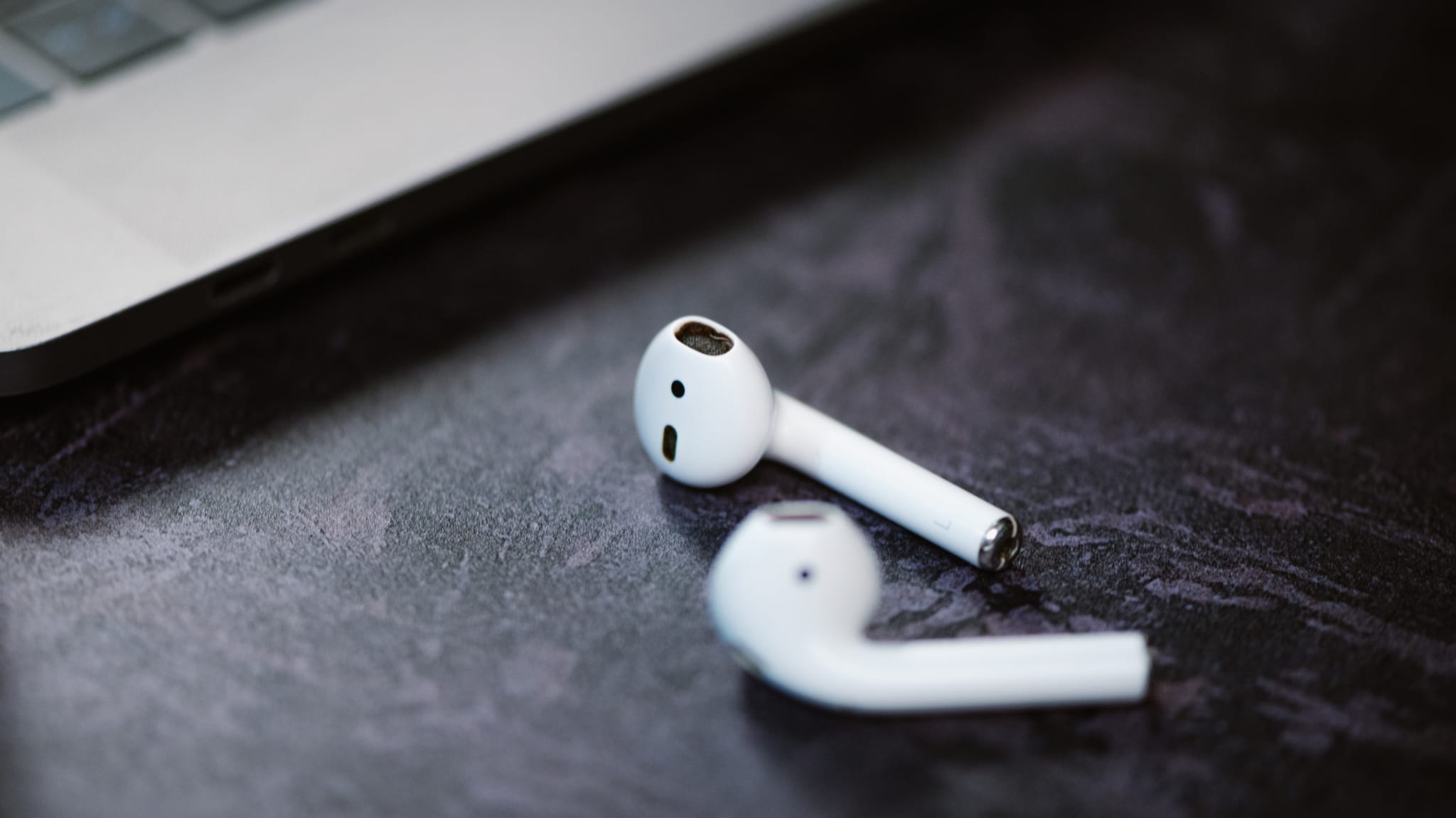 A pair of AirPods is pictured next to a laptop