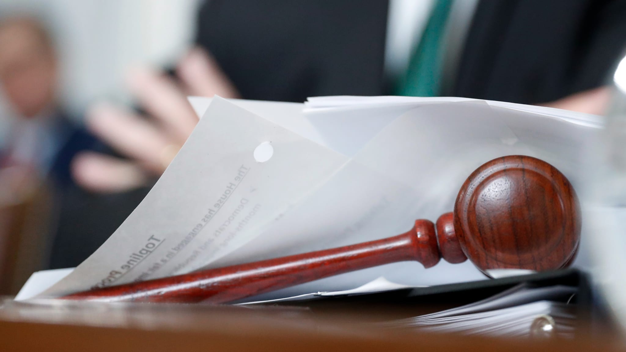 A gavel sits on the table among paperwork.