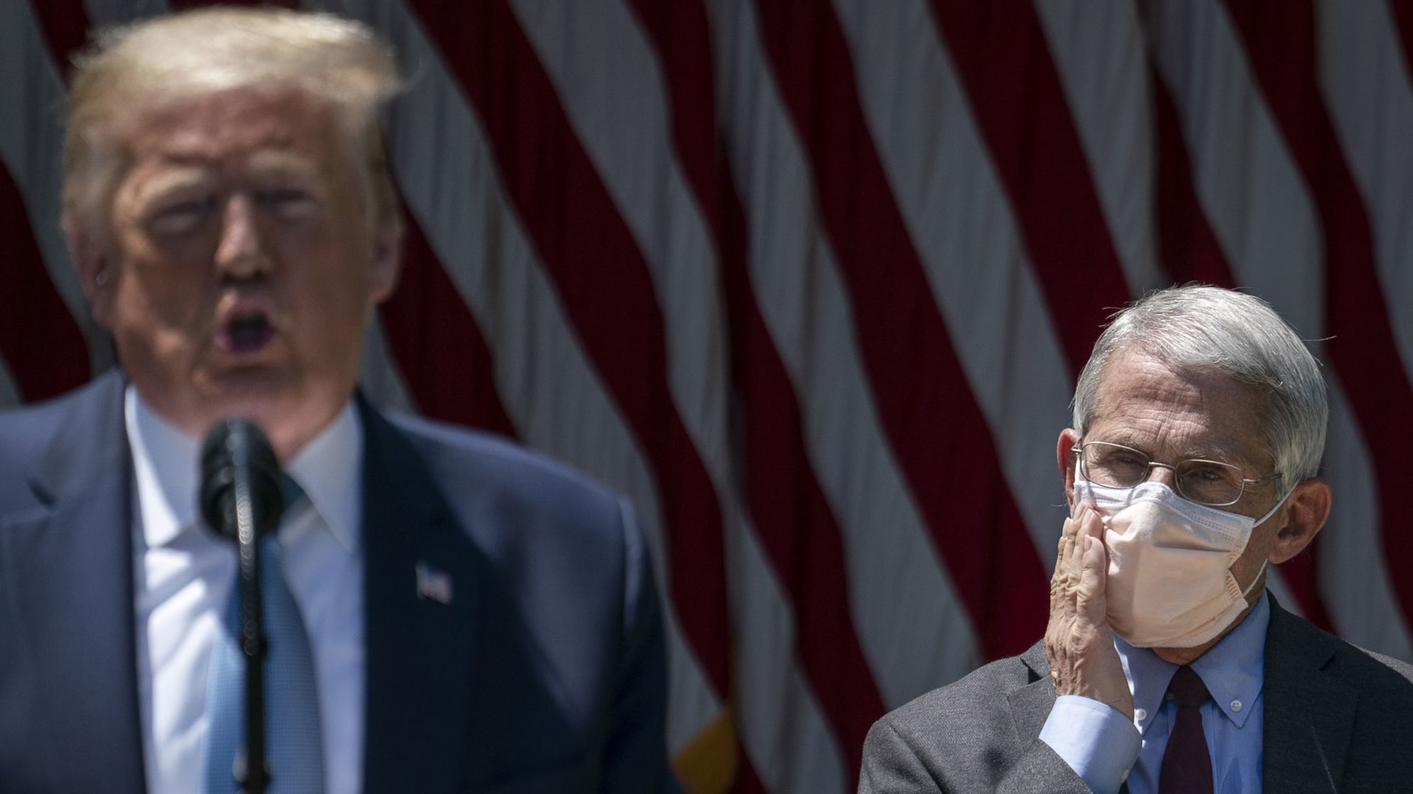 Donald Trump speaks as Anthony Fauci listens in the background.