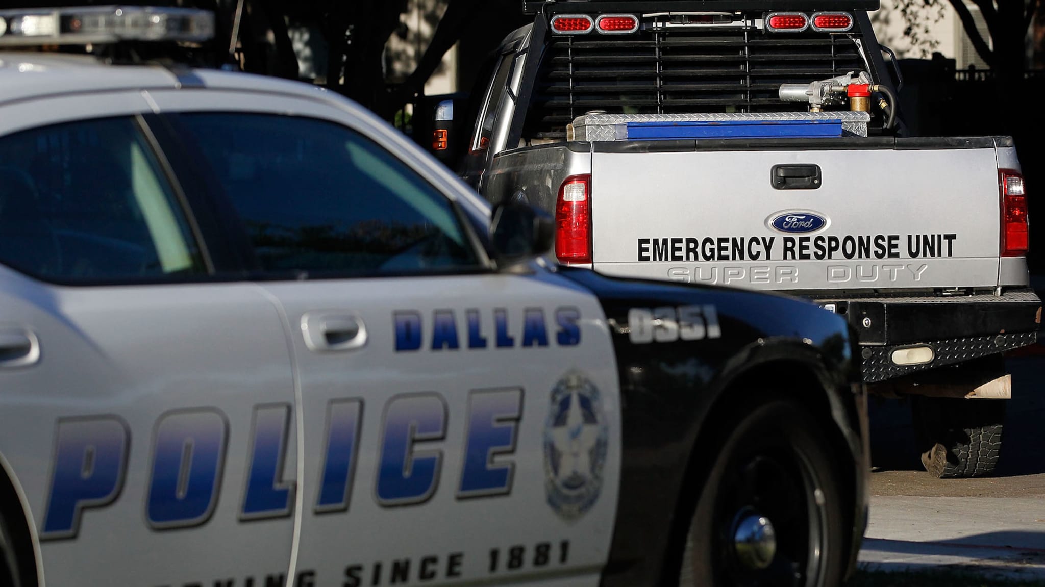 A Dallas police car and an emergency response vehicle sit in the parking lot.