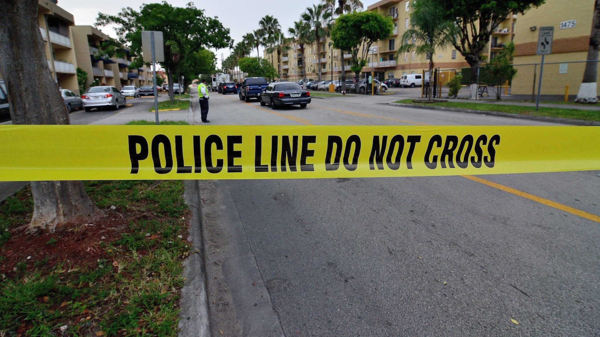 Police tape blocks the street to an apartment building