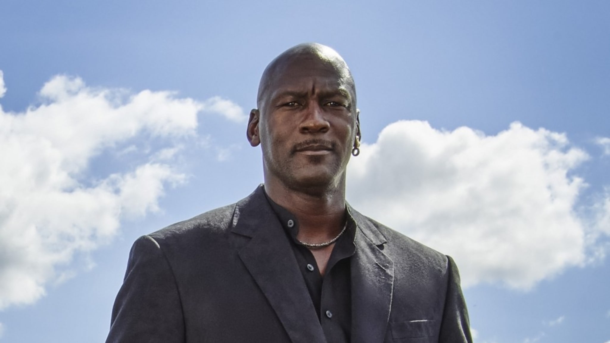 Michael Jordan in a suit in front of a blue sky