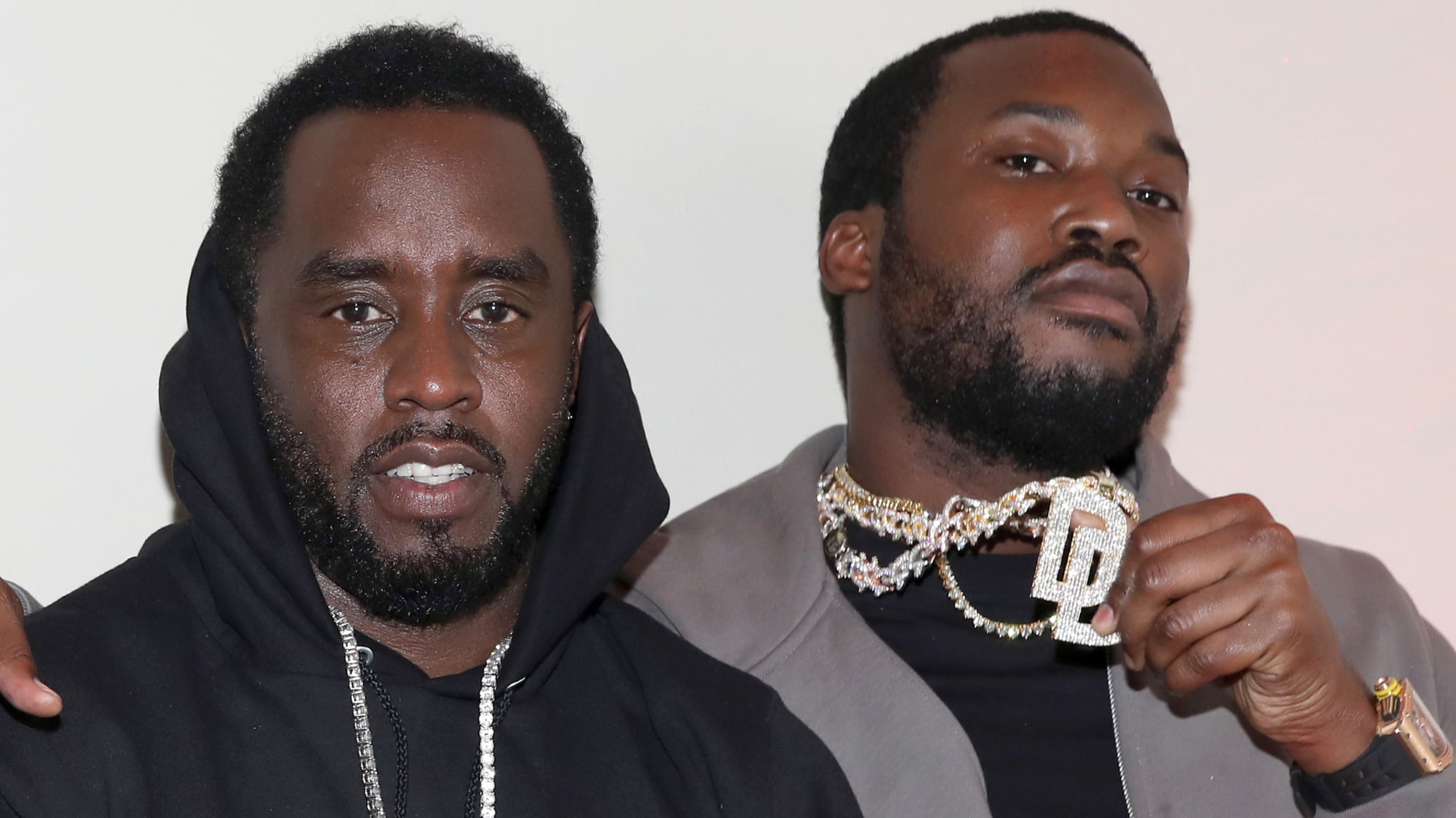 Sean "Diddy" Combs and Meek Mill pose together, both wearing jewelry and casual attire.