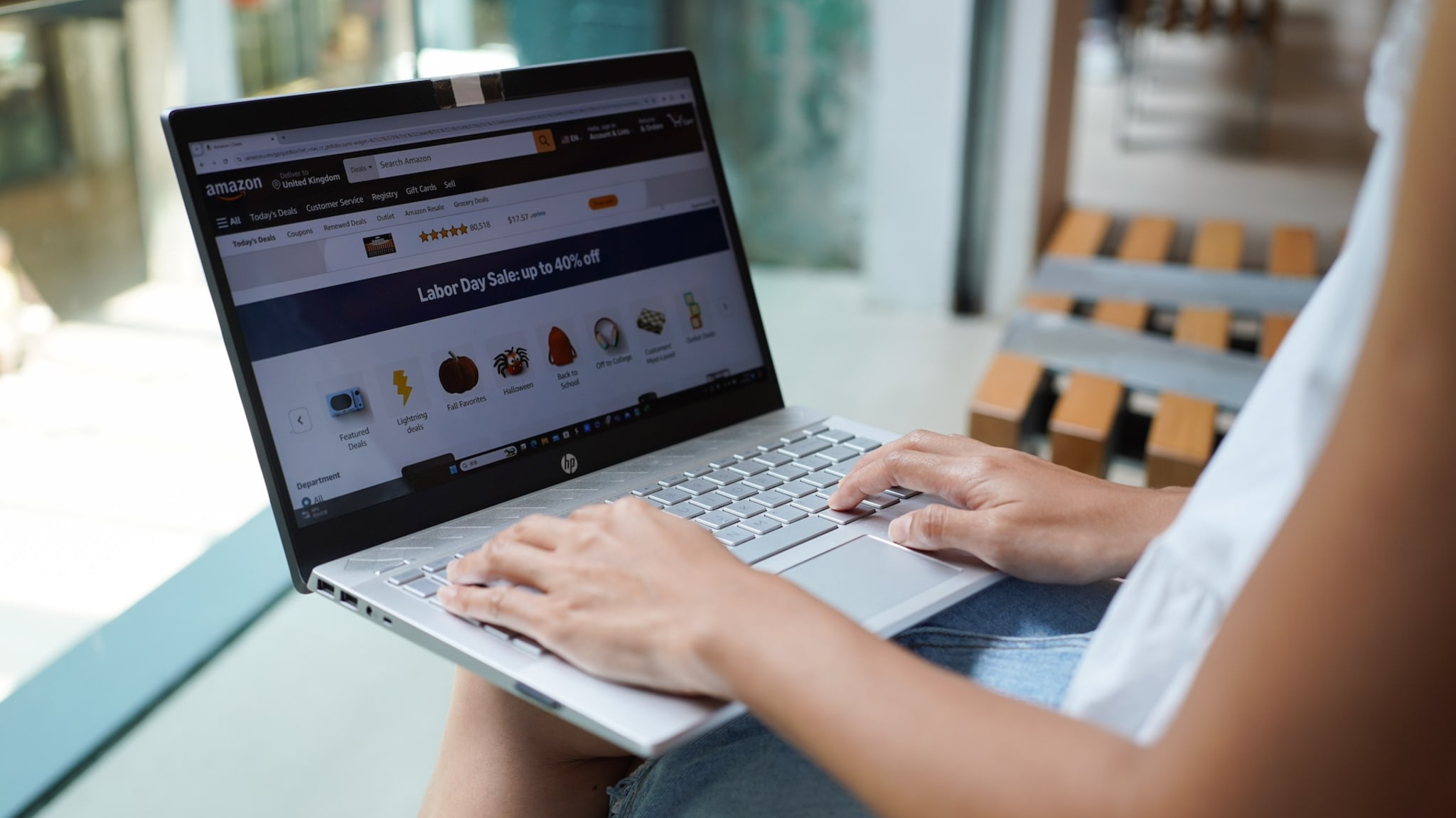 Person shopping online on a laptop, browsing a Labor Day sale on Amazon's website.