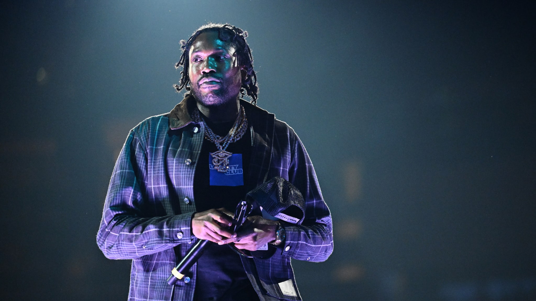 Meek Mill performs onstage with mic in hand.