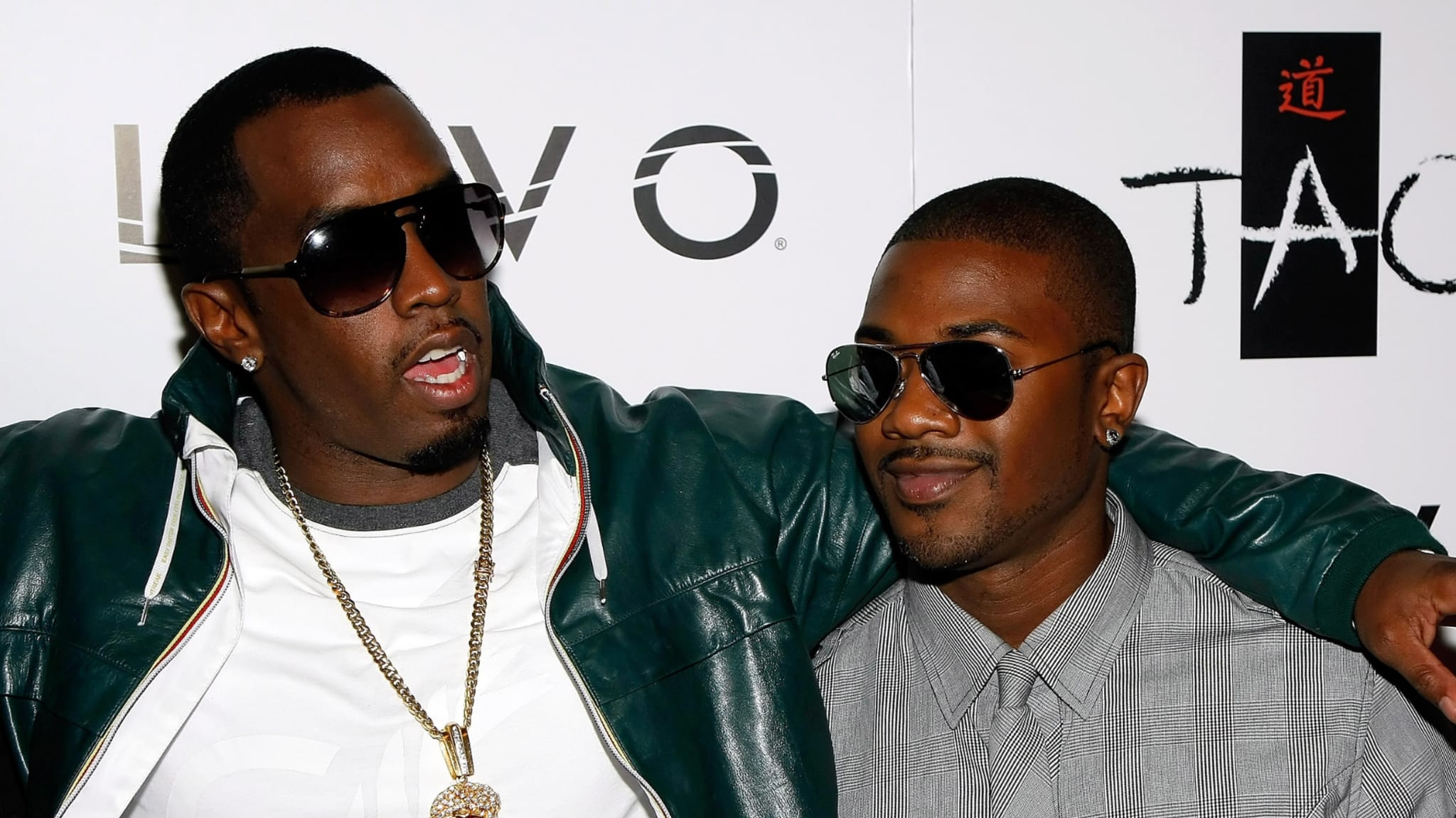 Sean "Diddy" Combs and Ray J, both wearing sunglasses, pose together at an event.