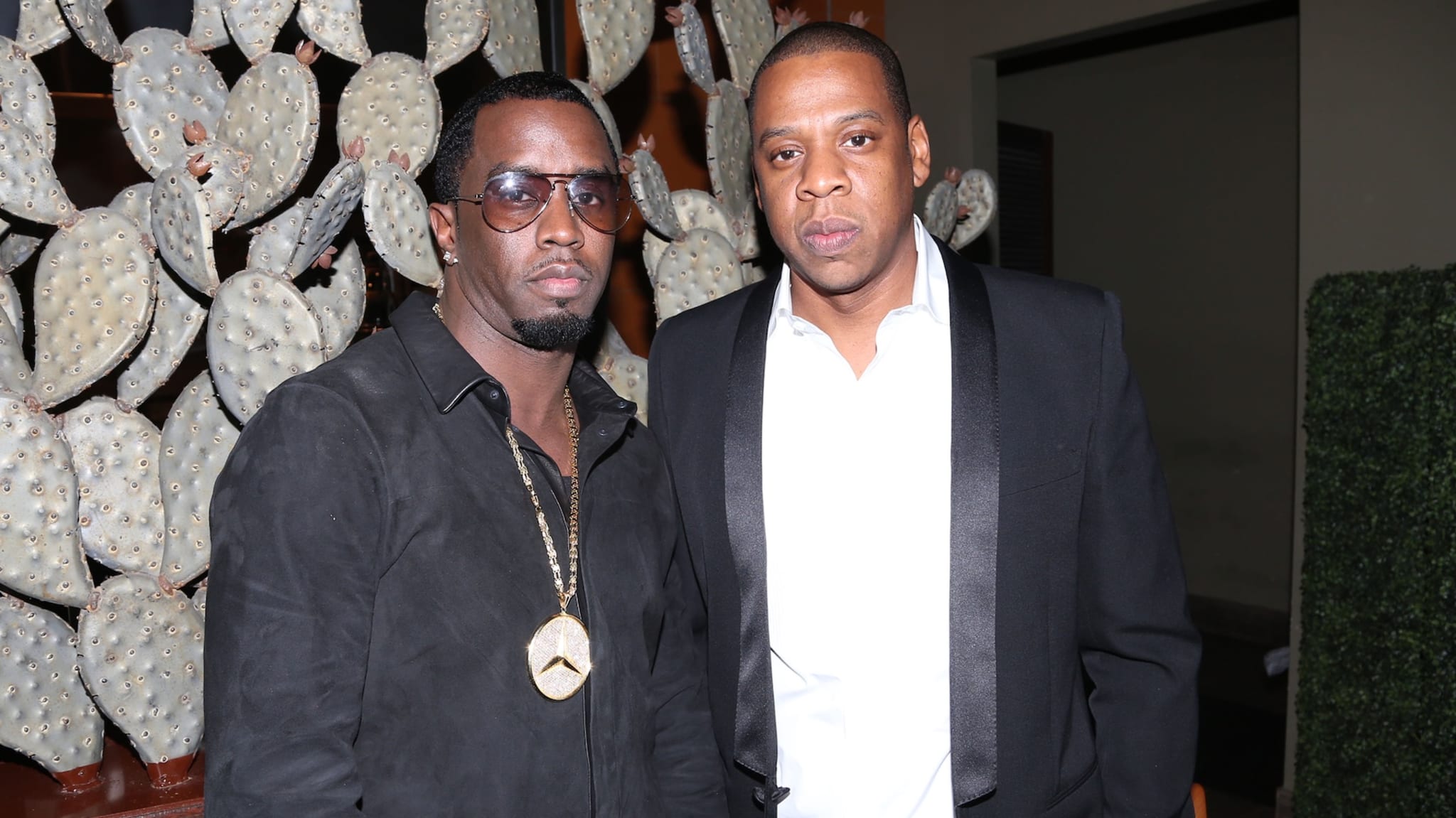 Sean "Diddy" Combs and Jay-Z pose together, both wearing suits.