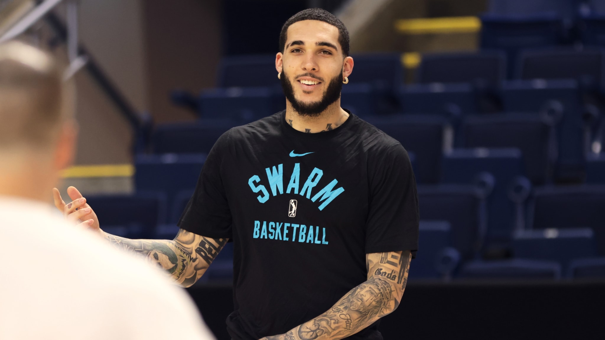 LiAngelo wearing a "Swarm Basketball" shirt smiles during practice on a court.