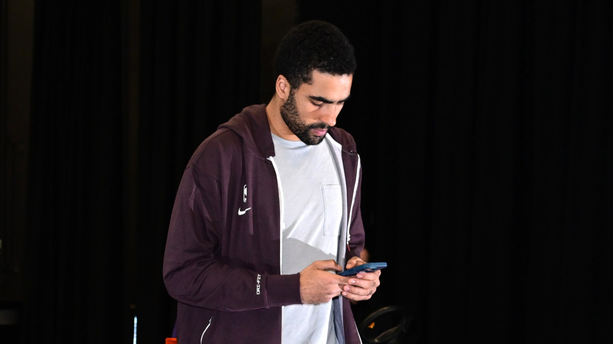 Jontay Porter in a casual outfit, holding a phone.