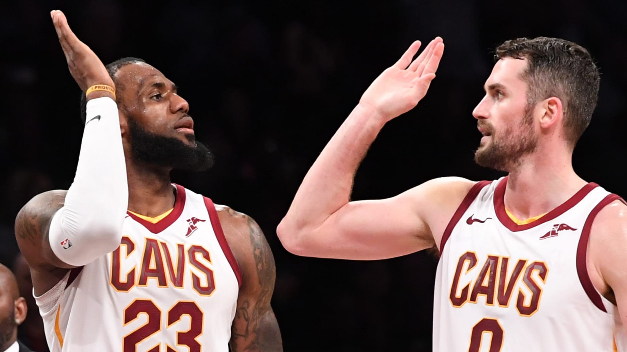 LeBron James and Kevin Love high-five in Cleveland Cavaliers jerseys during a basketball game.