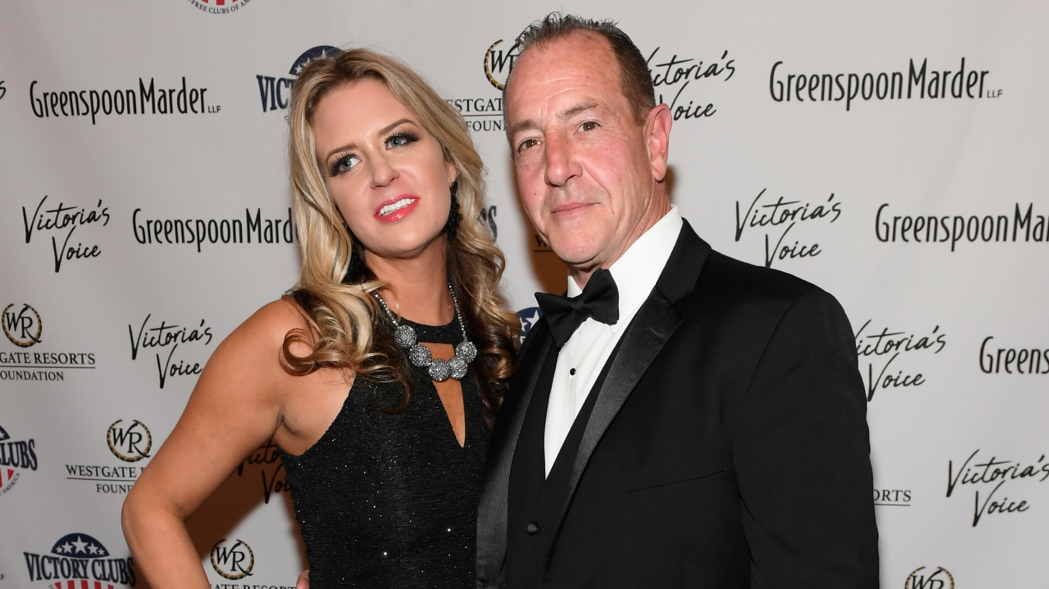 Kate Major and Michael Lohan in formal attire pose on a red carpet with a backdrop.