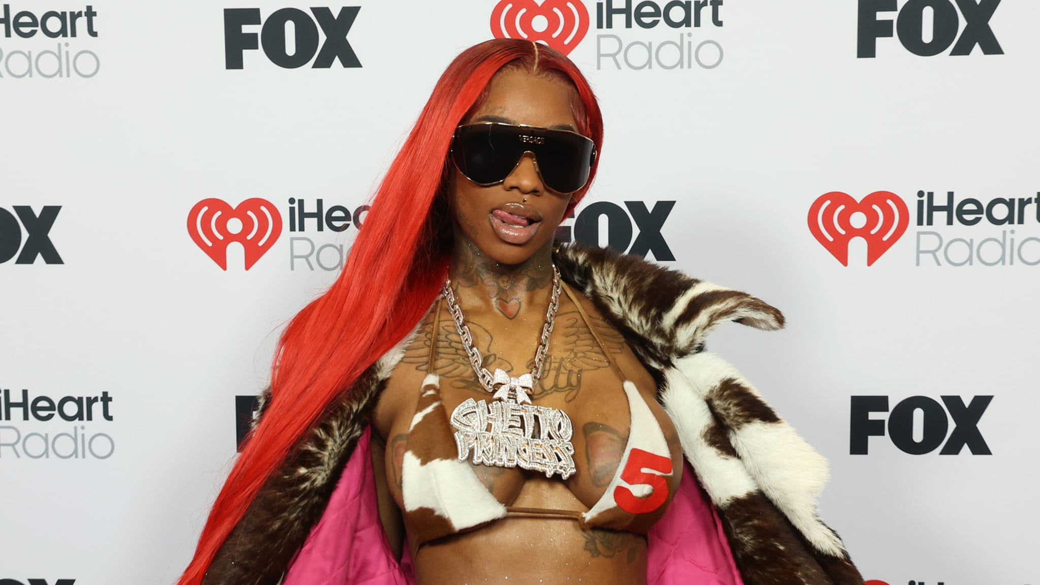 Sexyy Red poses at an event with iHeart Radio and FOX logos in the background.