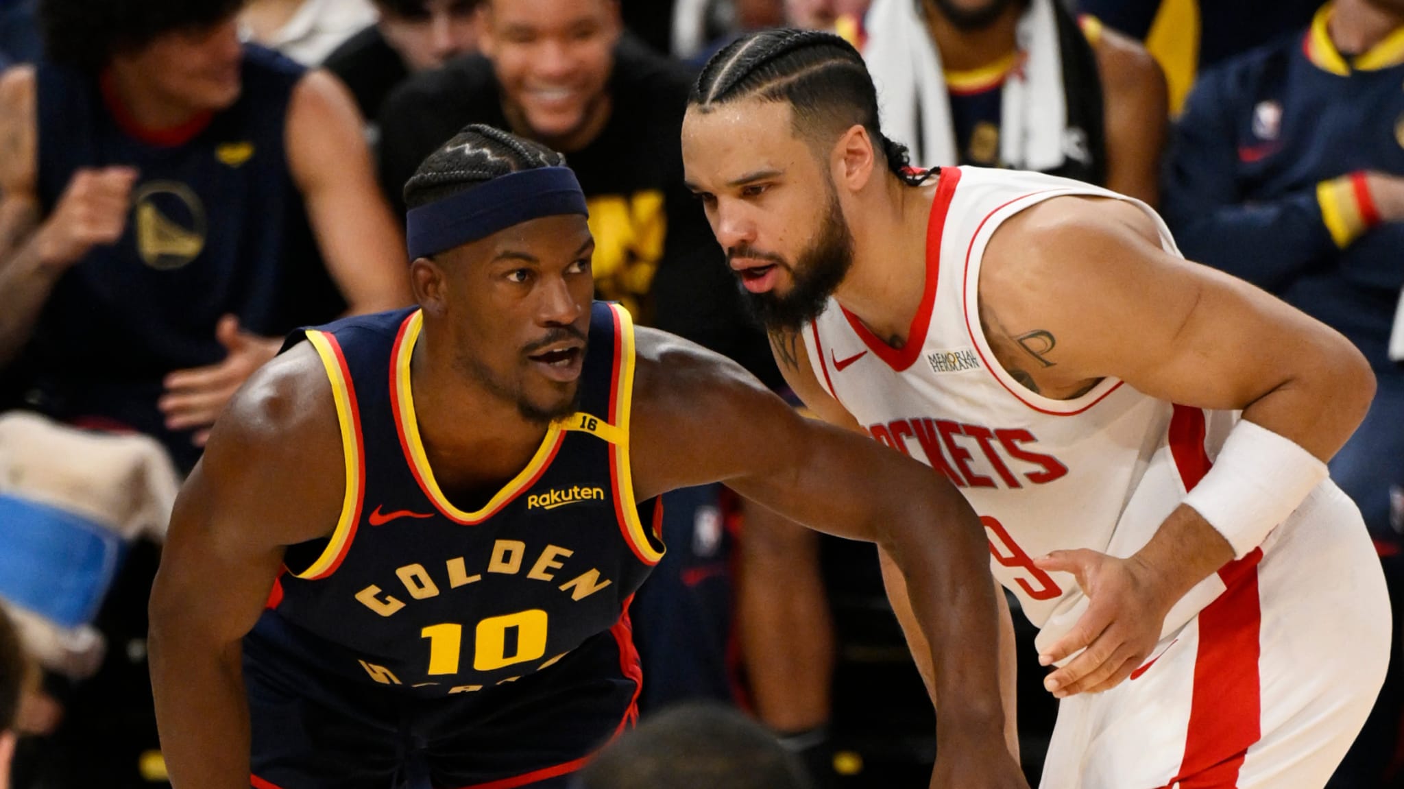 Two basketball players on the court, one in a Golden State Warriors jersey and the other in a Houston Rockets jersey, in action.