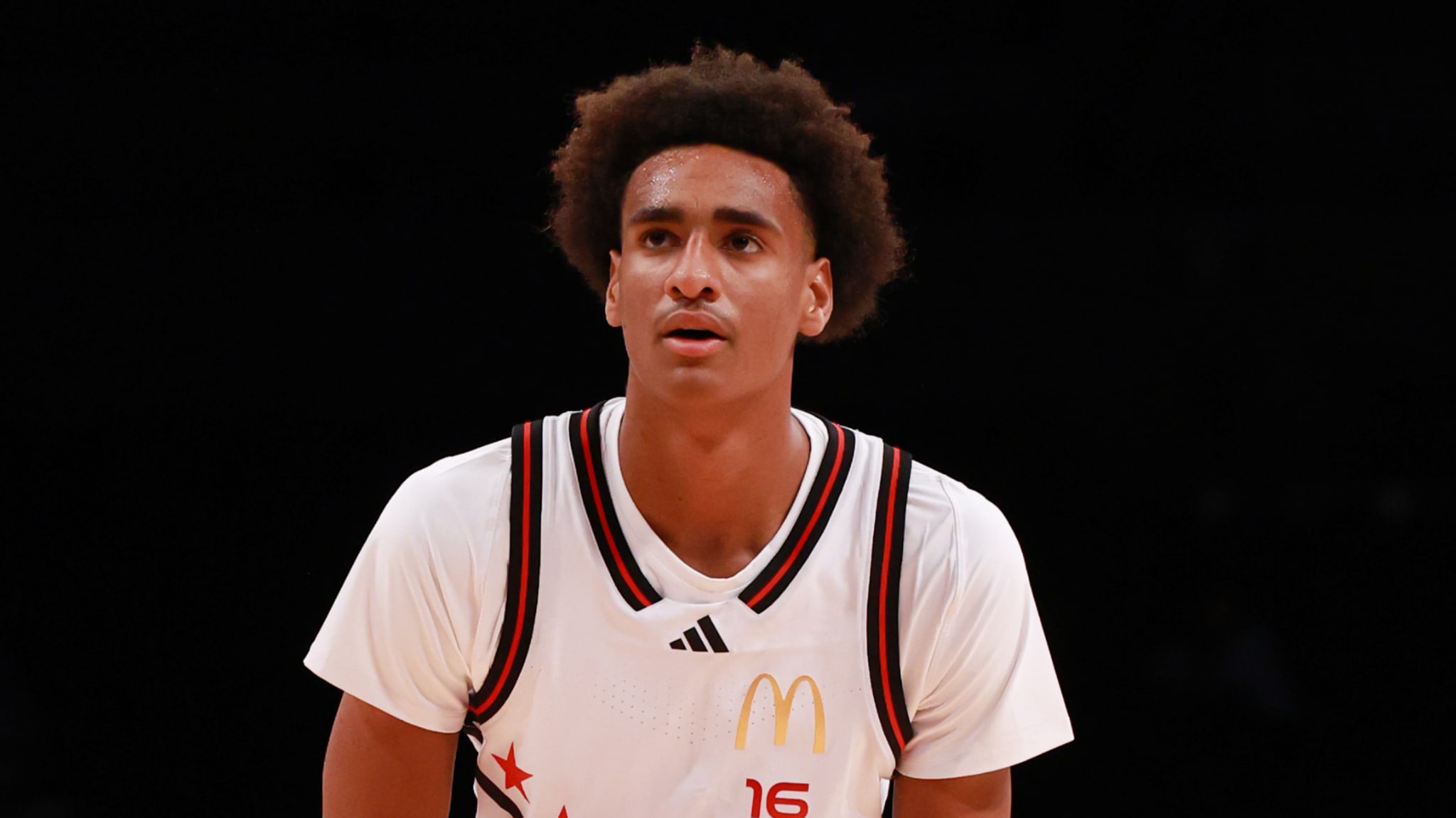 A basketball player in a white jersey with a McDonald's logo, focused during a game.