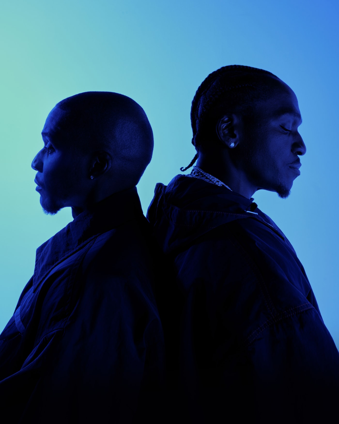 Two men stand back-to-back in profile, silhouetted against a blue gradient background, wearing dark clothing.