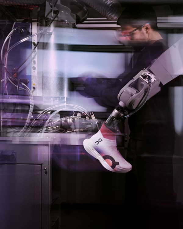 A person with a prosthetic arm works with machines in a high-tech laboratory setting. The image is dynamic, showing motion blur and a focus on technology
