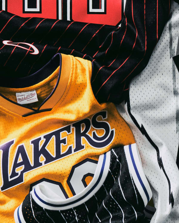 A collection of basketball jerseys, including a yellow Lakers jersey and a white jersey with "YVL" and "00" on it.