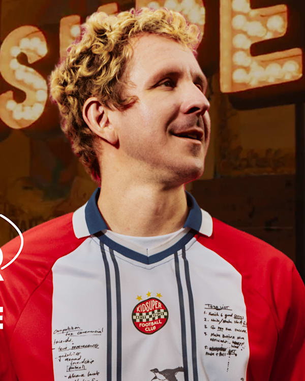 Colm Dillane, aka KidSuper, in a red and white soccer jersey, with "The Art of Soccer" text in the background.