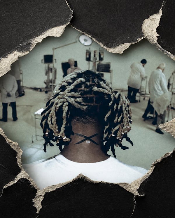 A person with braided hair is viewed from behind through a torn paper hole, revealing a laboratory scene with people in lab coats.