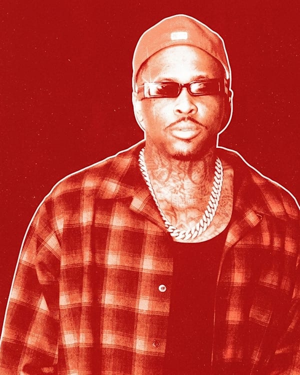 YG wearing sunglasses, a cap, a plaid shirt, and a chain necklace, in a red-tinted image.