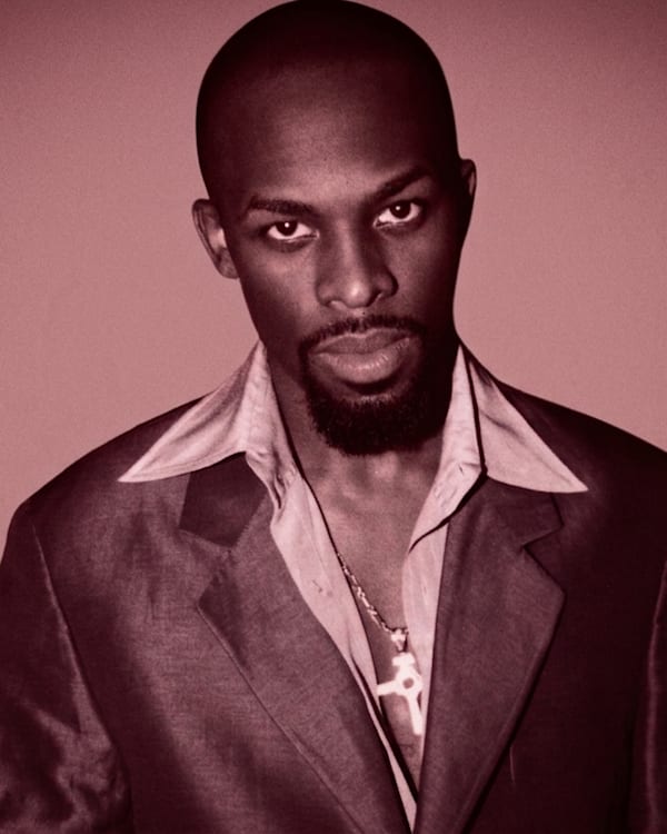 Joe in a blue suit stands against a decorative background with star patterns, looking directly at the camera.