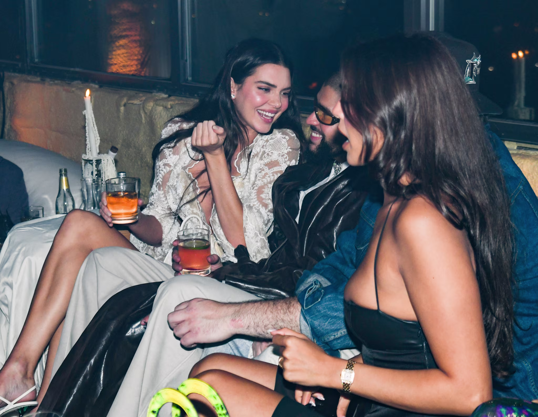 Three people lounging, one in a leather jacket, interacting joyfully