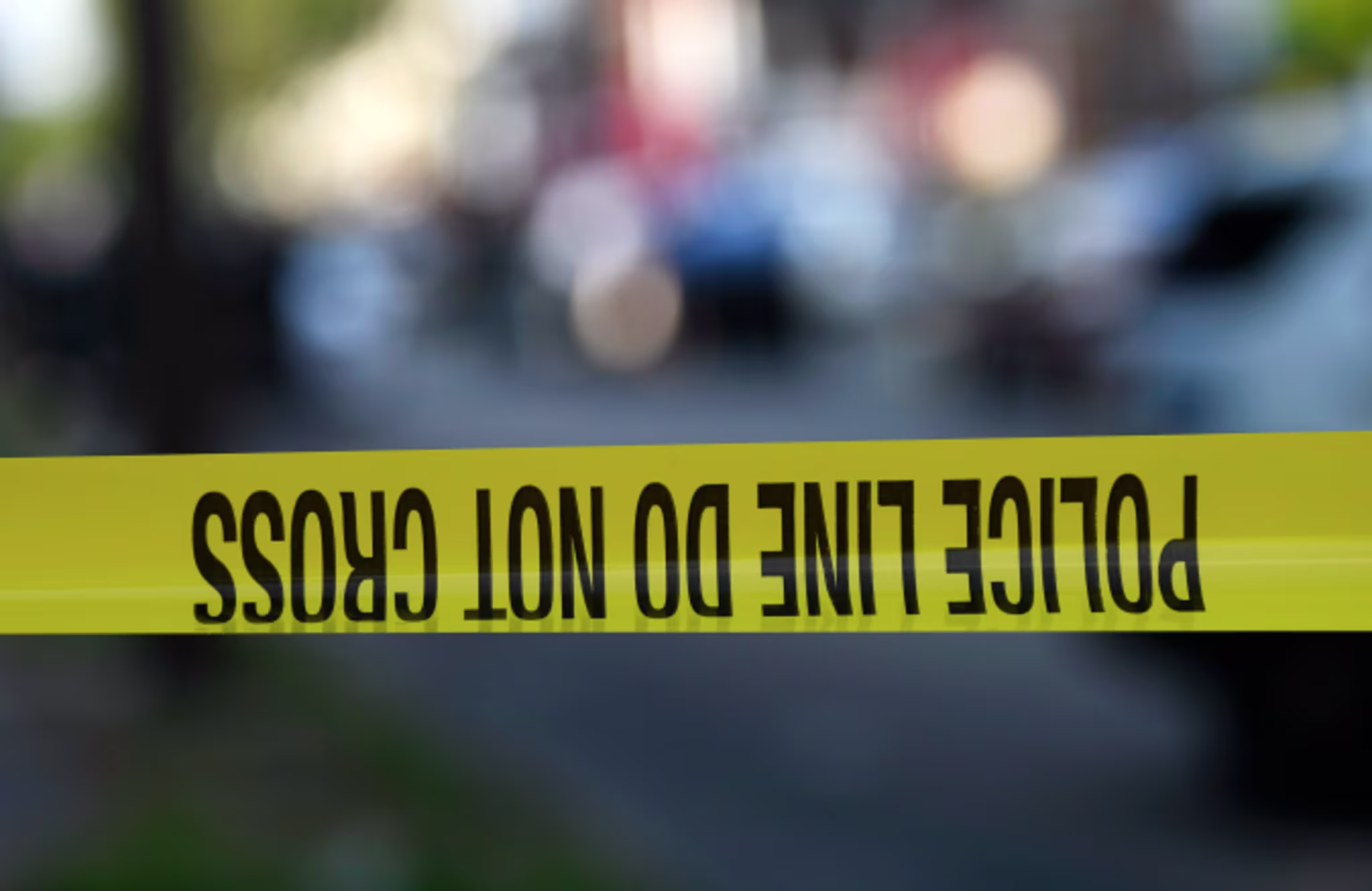 Police tape is stretched across a street near a residence during a shooting