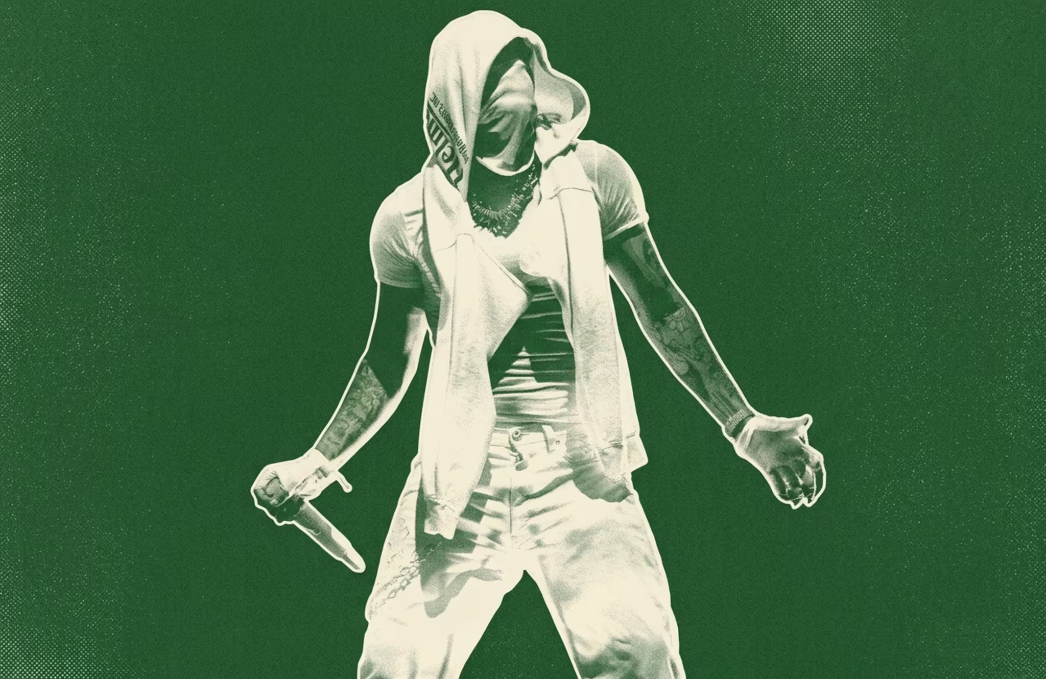 Yeat in a hooded outfit holds a microphone, surrounded by vibrant green and red lighting effects on stage.