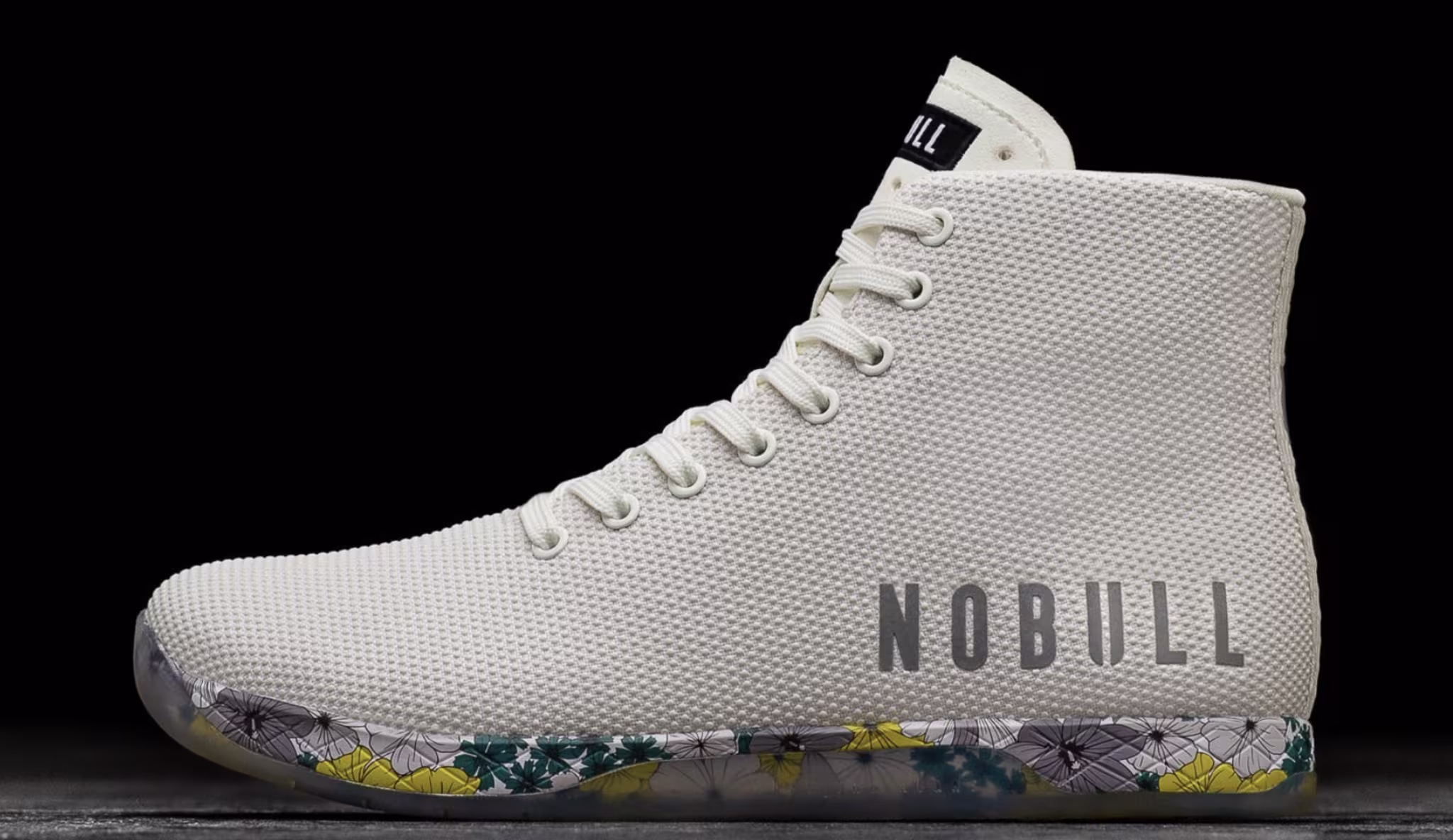 A high-top sneaker with a textured finish, a lace-up front, and the brand name "NOBULL" printed on the side. The sole features a multicolored pattern