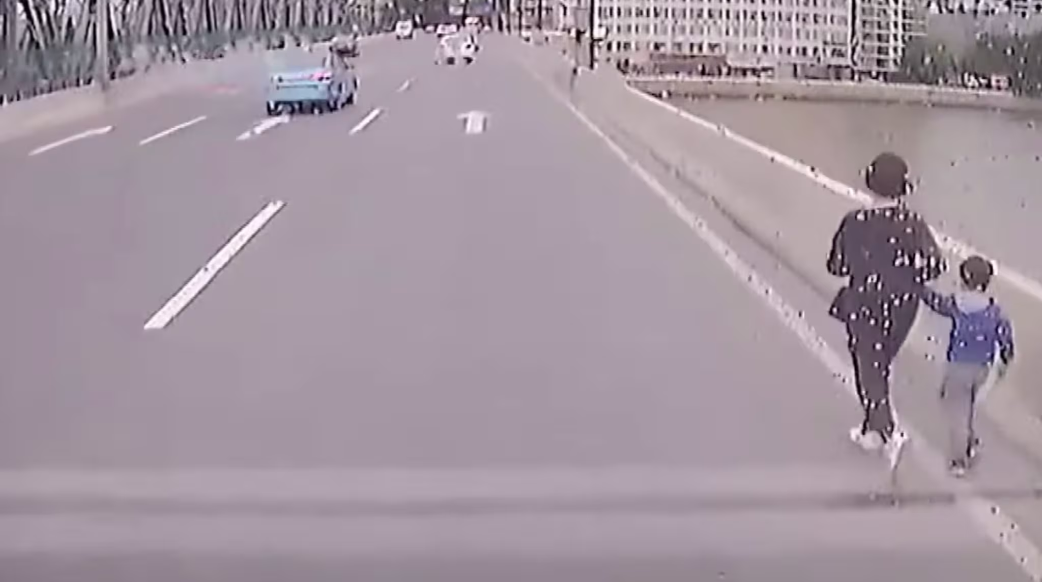 Two people walk on the street.