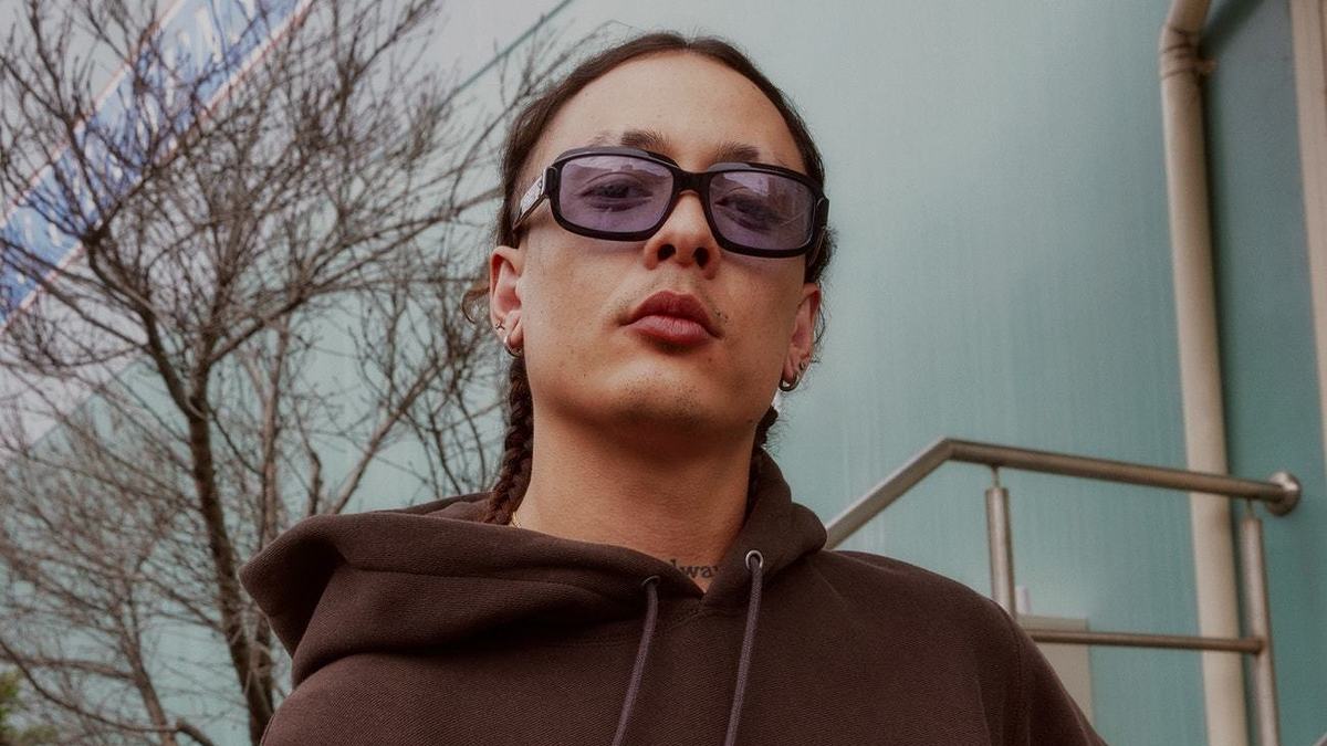Person in sunglasses and a casual Champion hoodie stands confidently outdoors