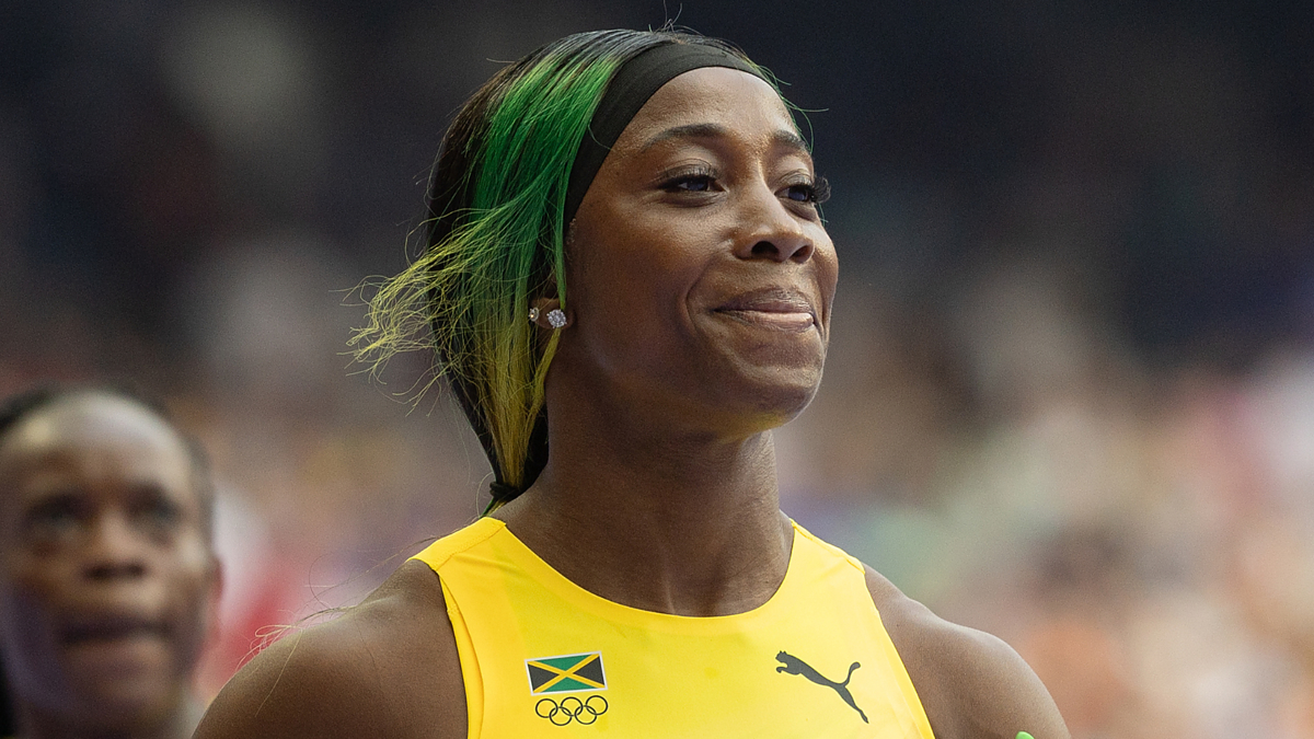 Sprinter Shelly-Ann Fraser-Pryce at an Olympic event, dressed in athletic wear with the Jamaican flag and Puma logo on her top, smiling confidently