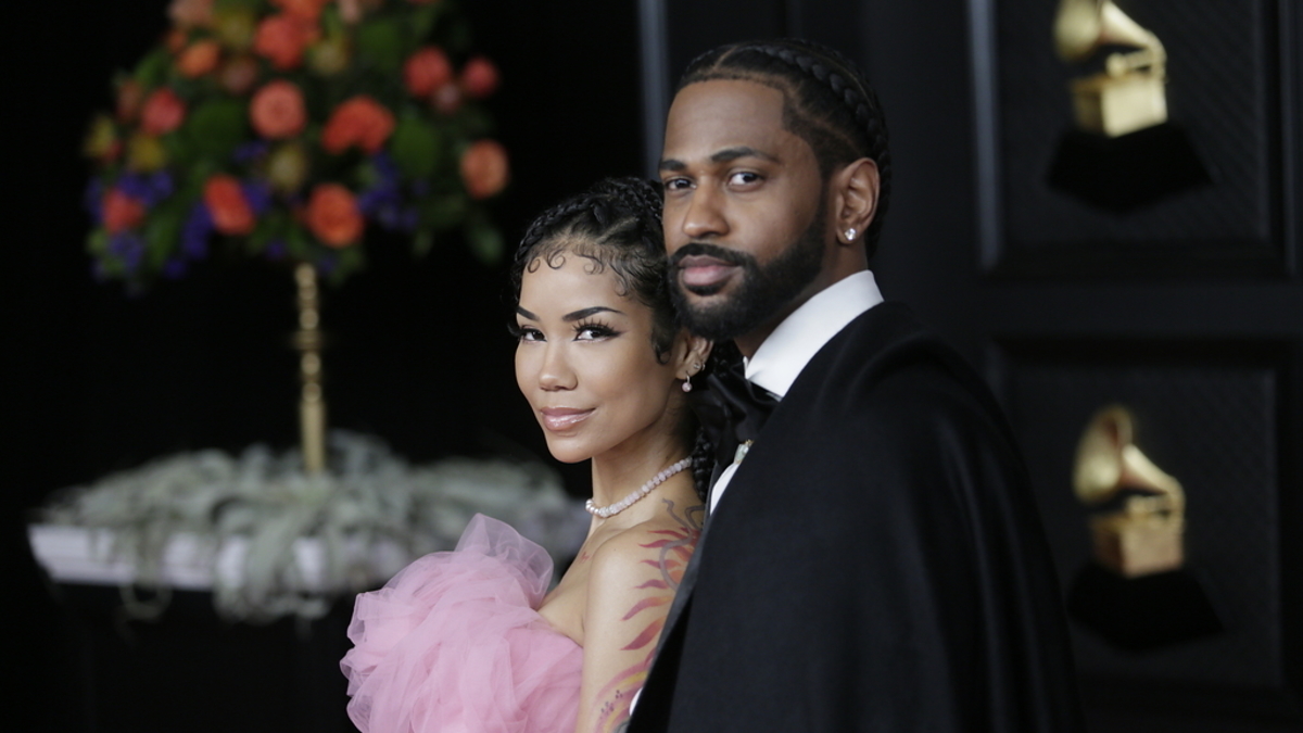 Jhené Aiko and Big Sean at a music award event, with Jhené wearing an elegant gown and Big Sean in a suit and cape