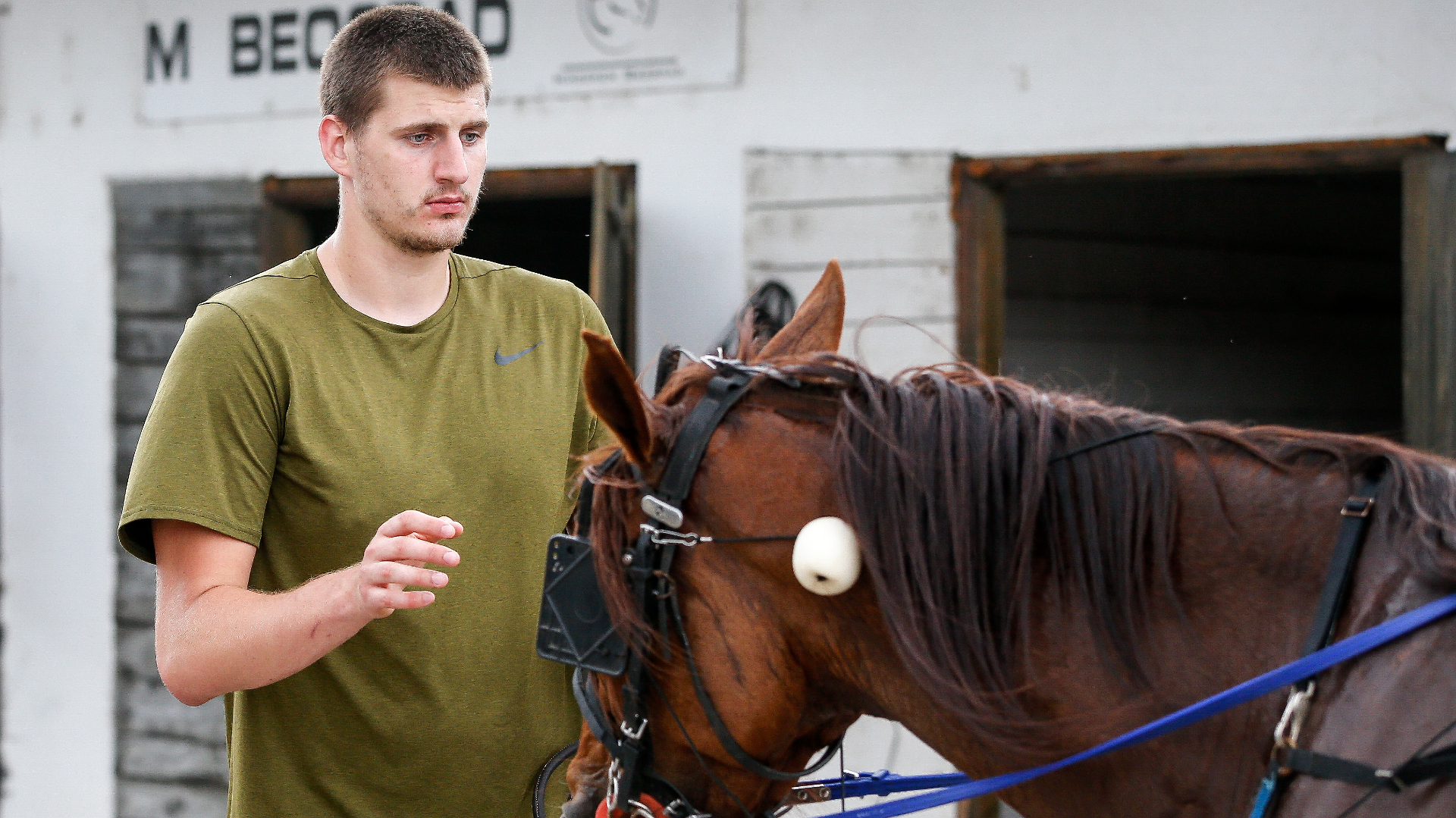 Nikola Jokic of the Denver Nuggets leads his horse to the stable area. 
