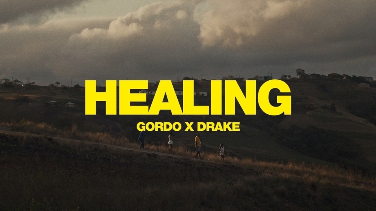 Text on image: "HEALING GORDO X DRAKE" with people walking in a hilly landscape background
