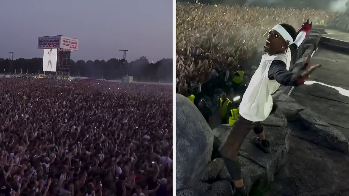 A large crowd gathers at Travis Scott's concert in Milan, Italy as he energetically sings on stage wearing a white jacket and black shorts