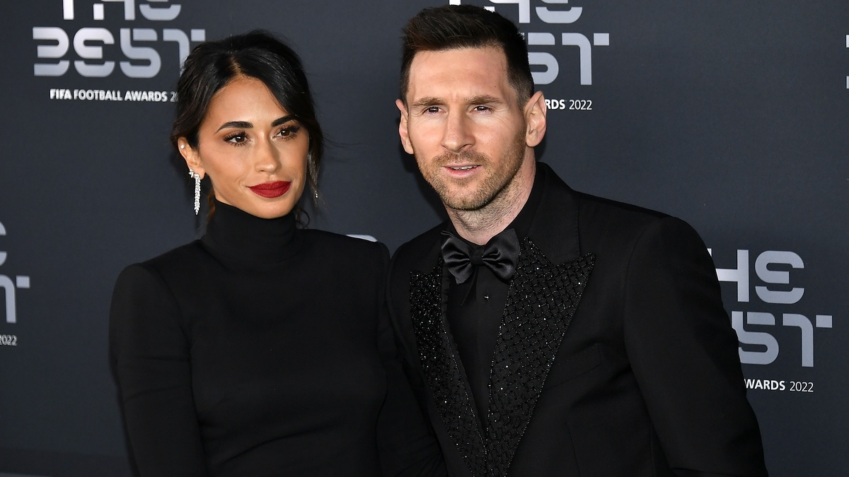 Lionel Messi and Antonela Roccuzzo at the FIFA Football Awards 2022, wearing elegant black outfits. Messi in a tailored suit with a bow tie, Roccuzzo in a turtleneck dress
