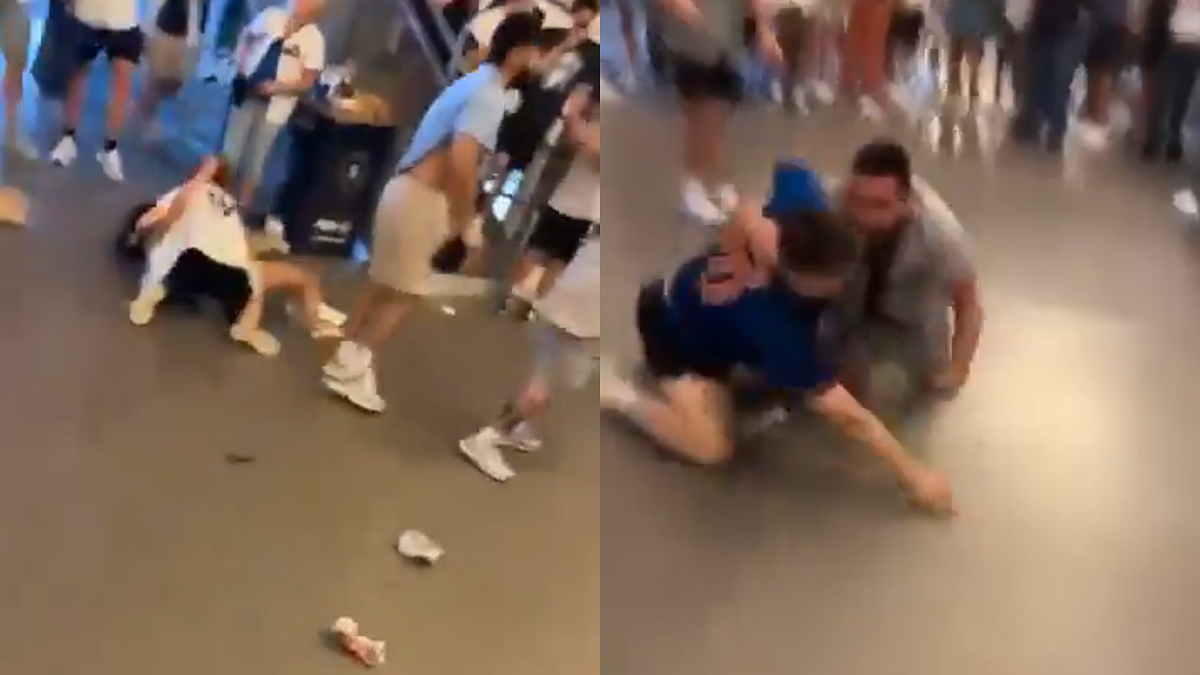 A crowded indoor scene shows two groups of people engaged in physical altercations on the floor. Trash and personal items are scattered around