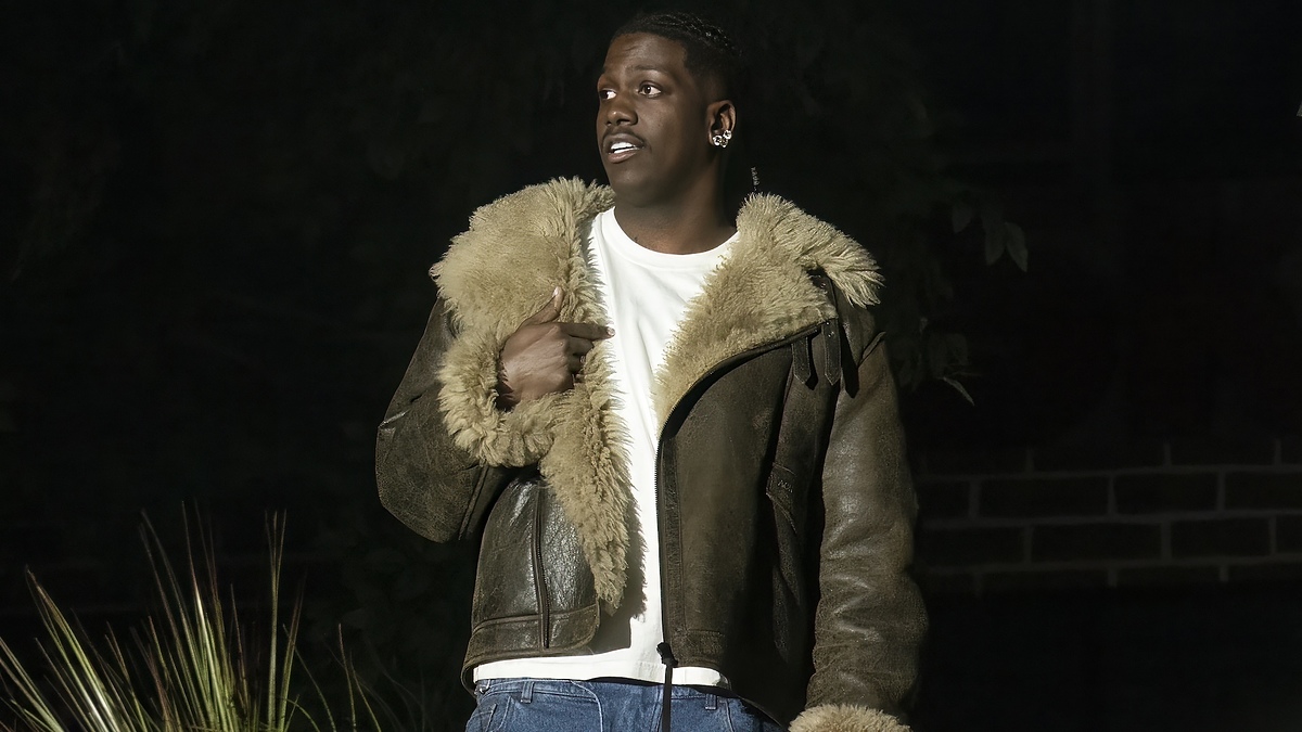 Lil Yachty poses outdoors in a wool-lined jacket, white shirt, and jeans, looking to his right