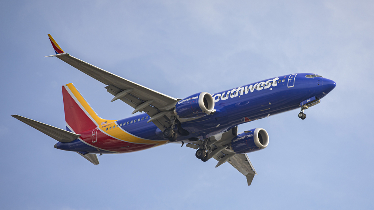 Southwest Airlines plane in flight with landing gear deployed against a clear sky